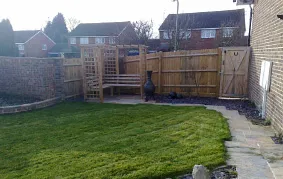 a backyard with a green lawn and a wooden fence